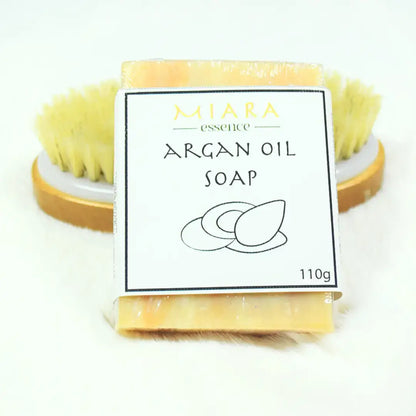 Miara Essence Argan Oil Natural Soap bar with a natural bristle brush, promoting glowing skin and hydration.