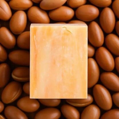 Miara Essence Argan Oil Natural Soap placed on argan nuts, emphasizing its nourishing properties for glowing skin.